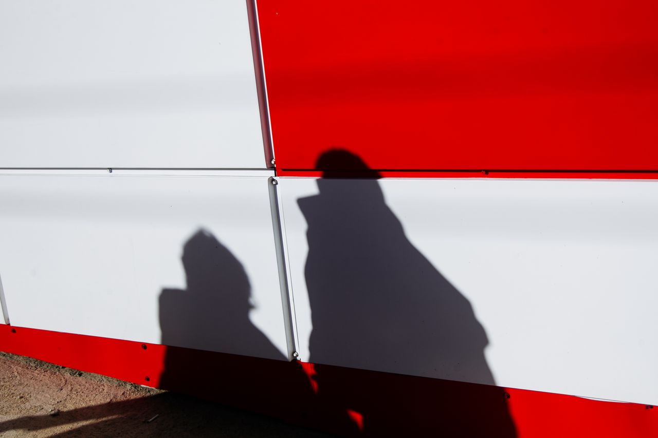 shadows of people on wall covered with white and red plastic panels in
