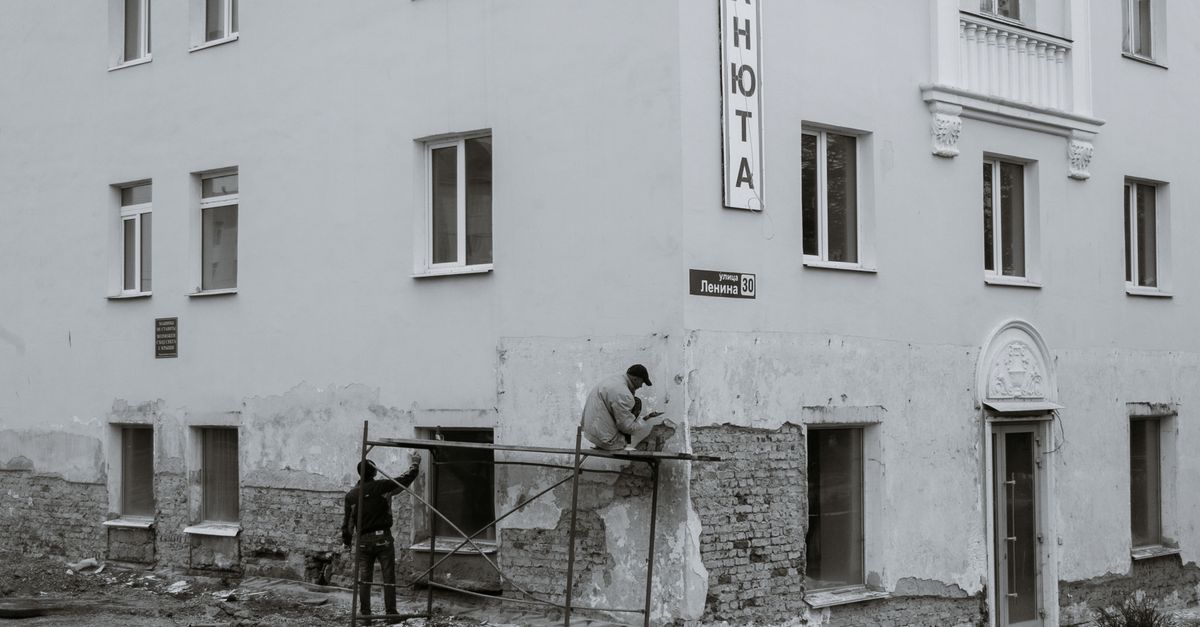 Handwerker sanieren die Außenwand eines Wohnhauses mit Gerüst und Dämmmaterial