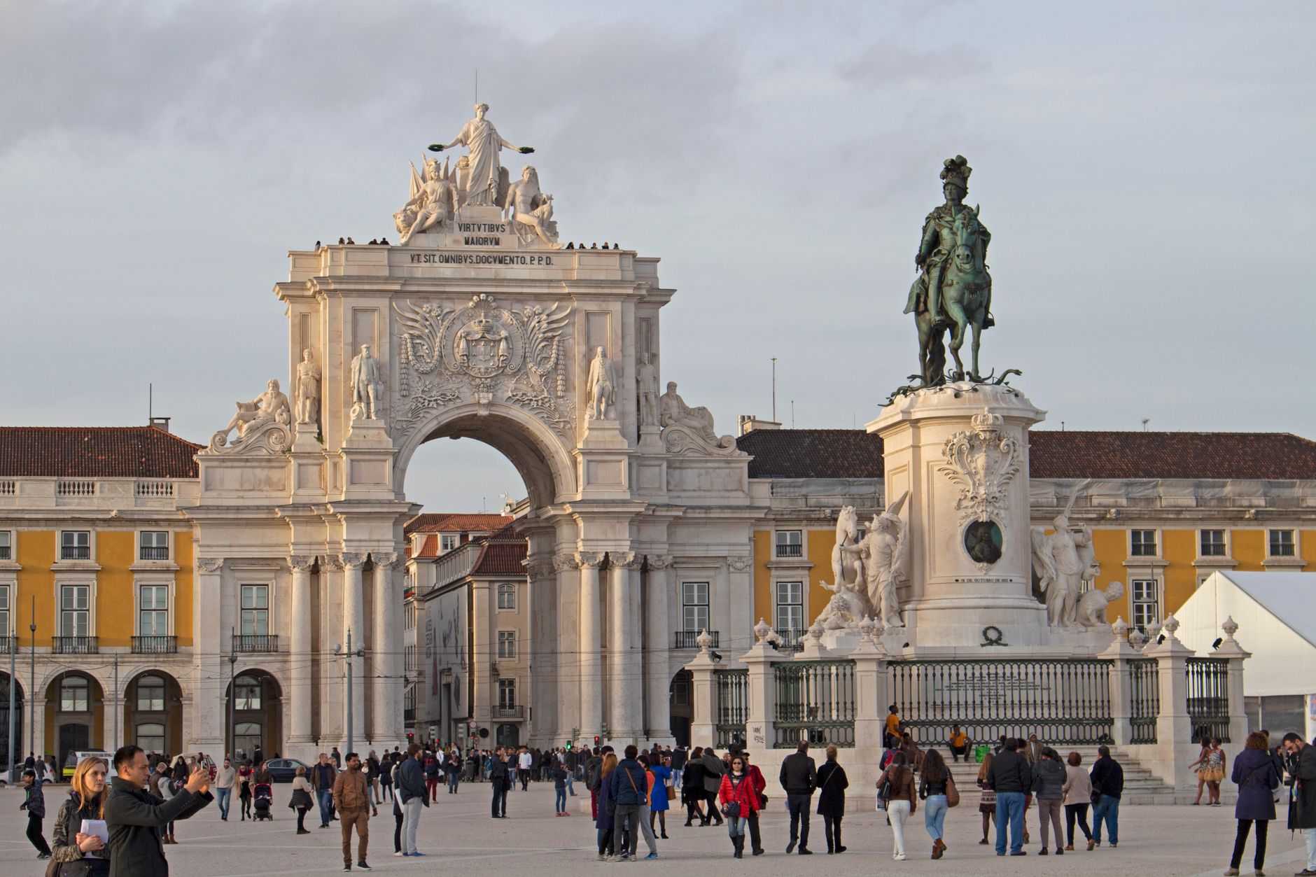 Bustling scene at Praça do Comércio, Lisbon featuring Arco da Rua Augusta and King José I statue.