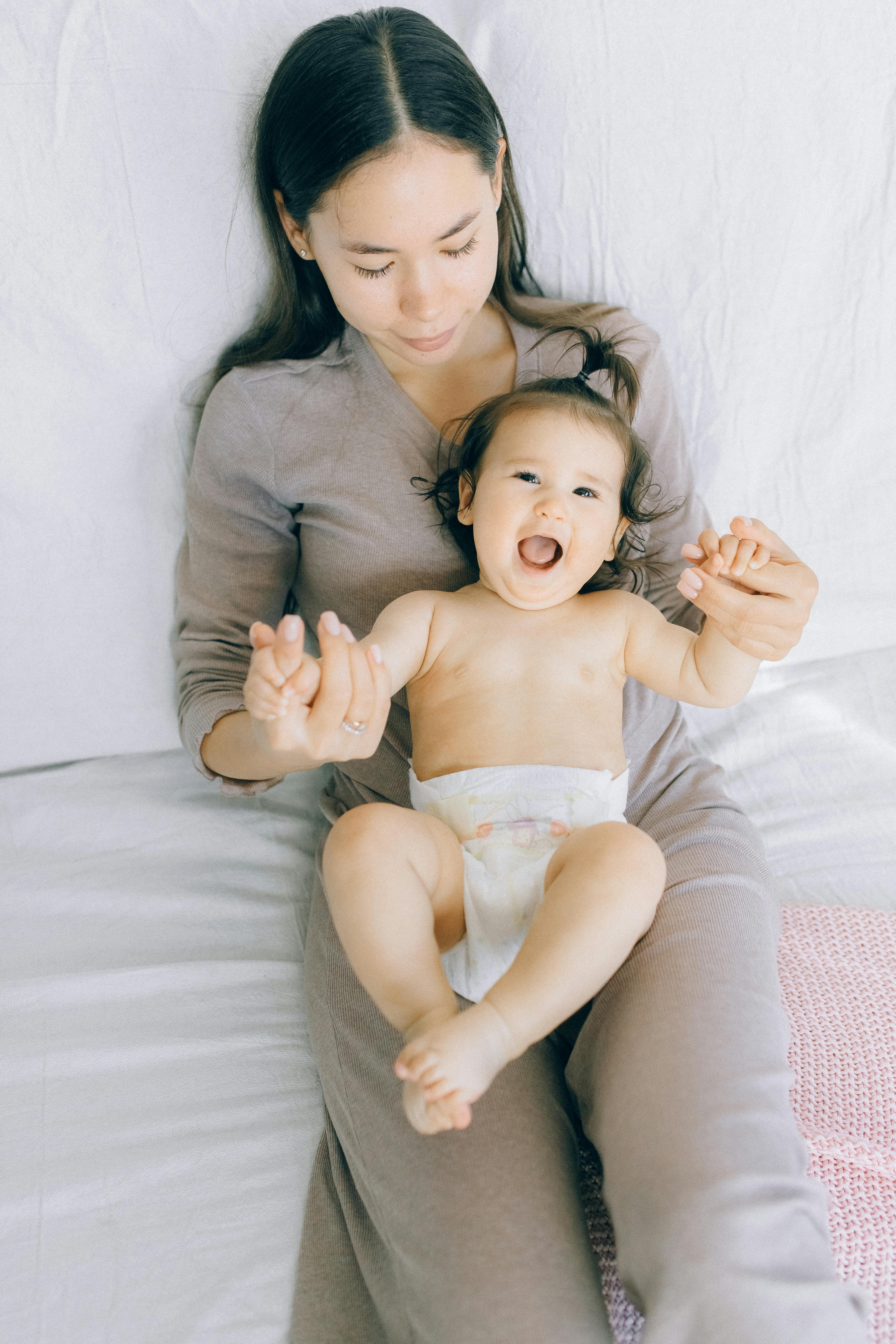 mother sitting on bed holding a baby