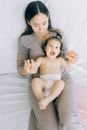 Mother Sitting on Bed Holding a Baby