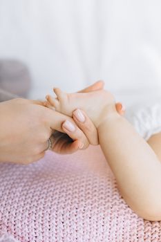 特写镜头中，婴儿的脚在柔软的粉色毯子上被轻轻按摩
