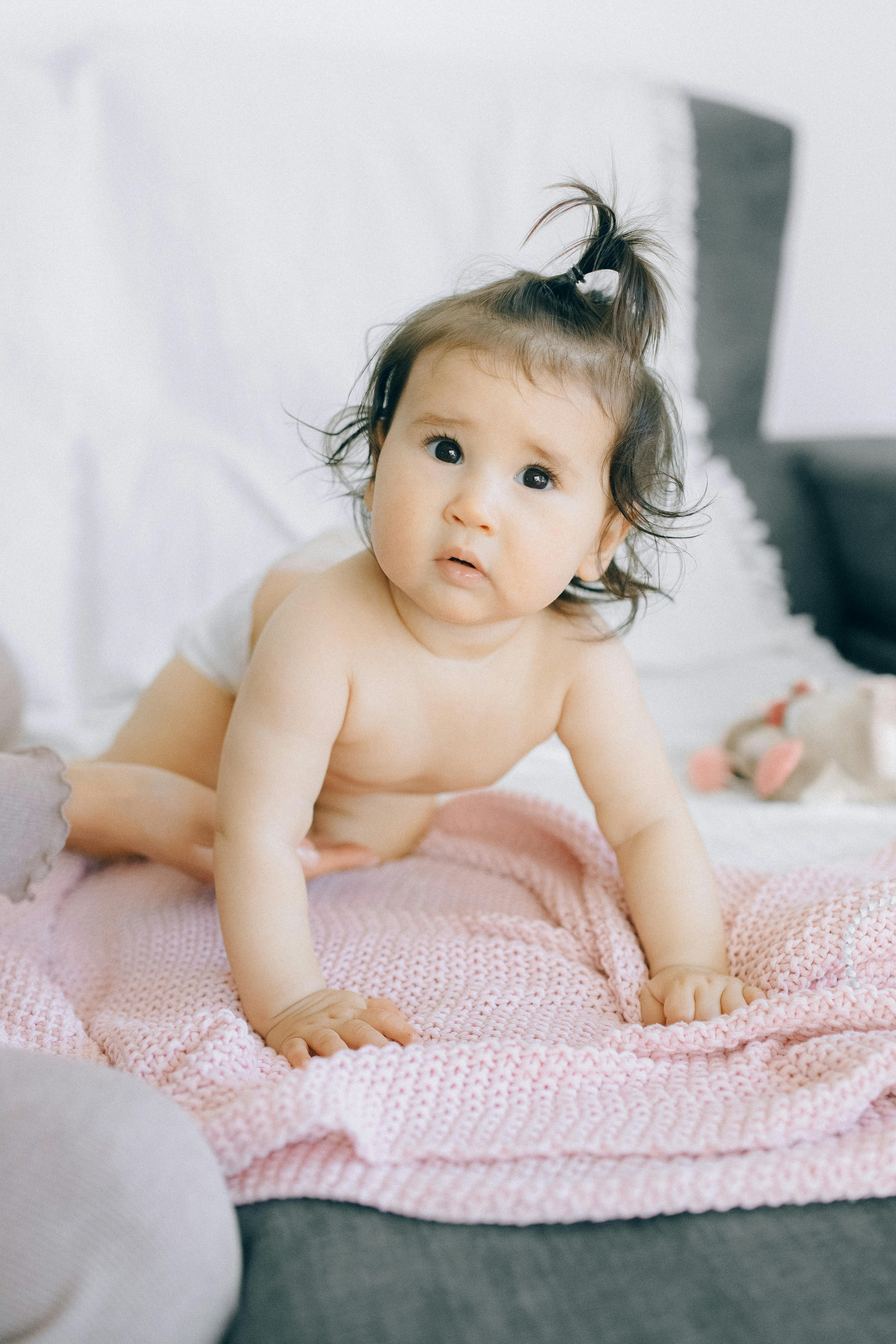 baby lying on pink and white bed