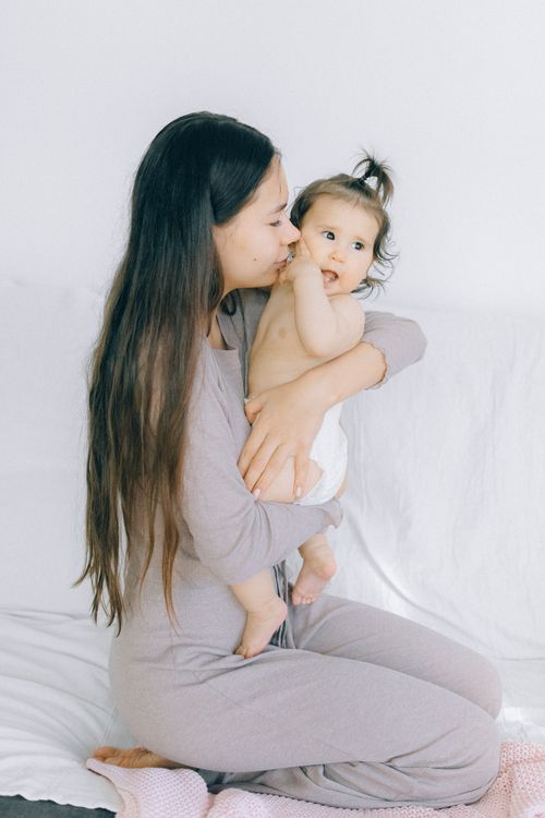 Free Loving mother holding her baby indoors, showcasing tender affection and family bond. Stock Photo