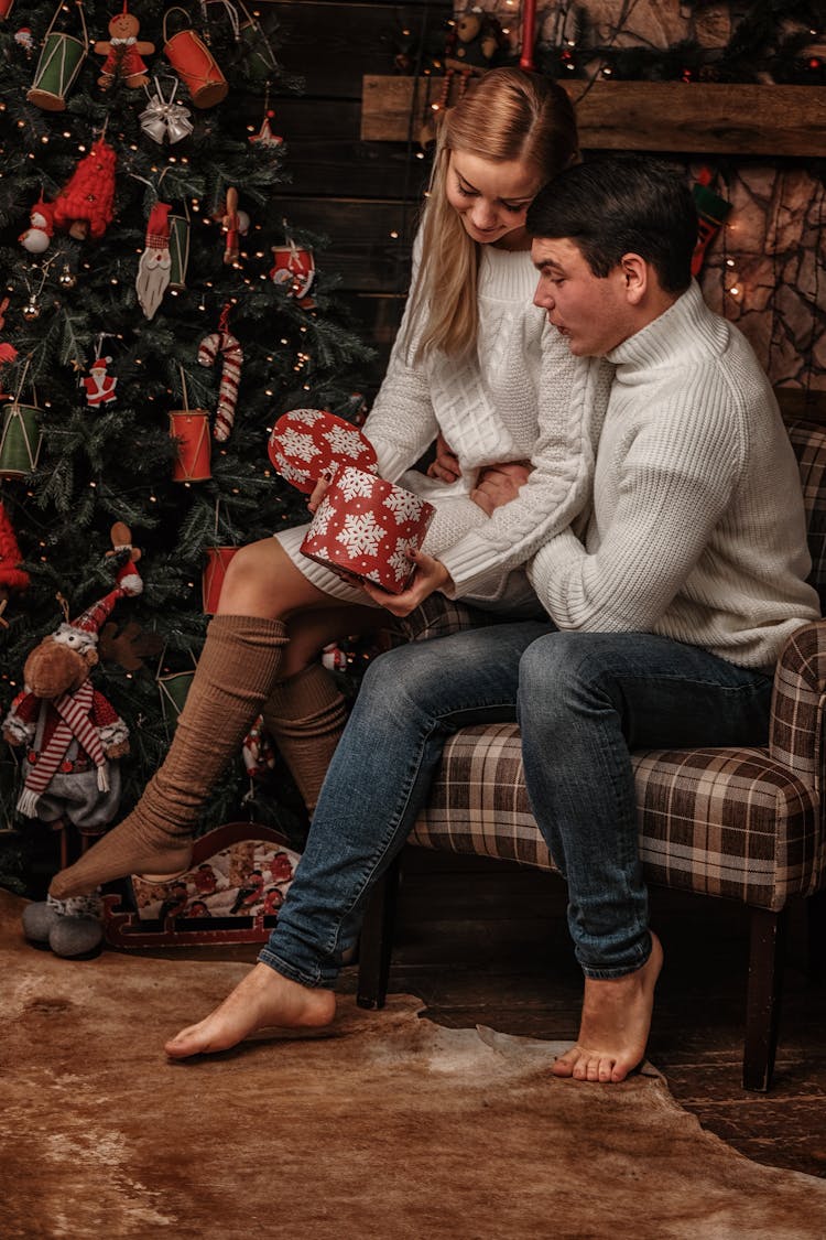 Young Couple Exchanging Gifts Near Christmas Tree