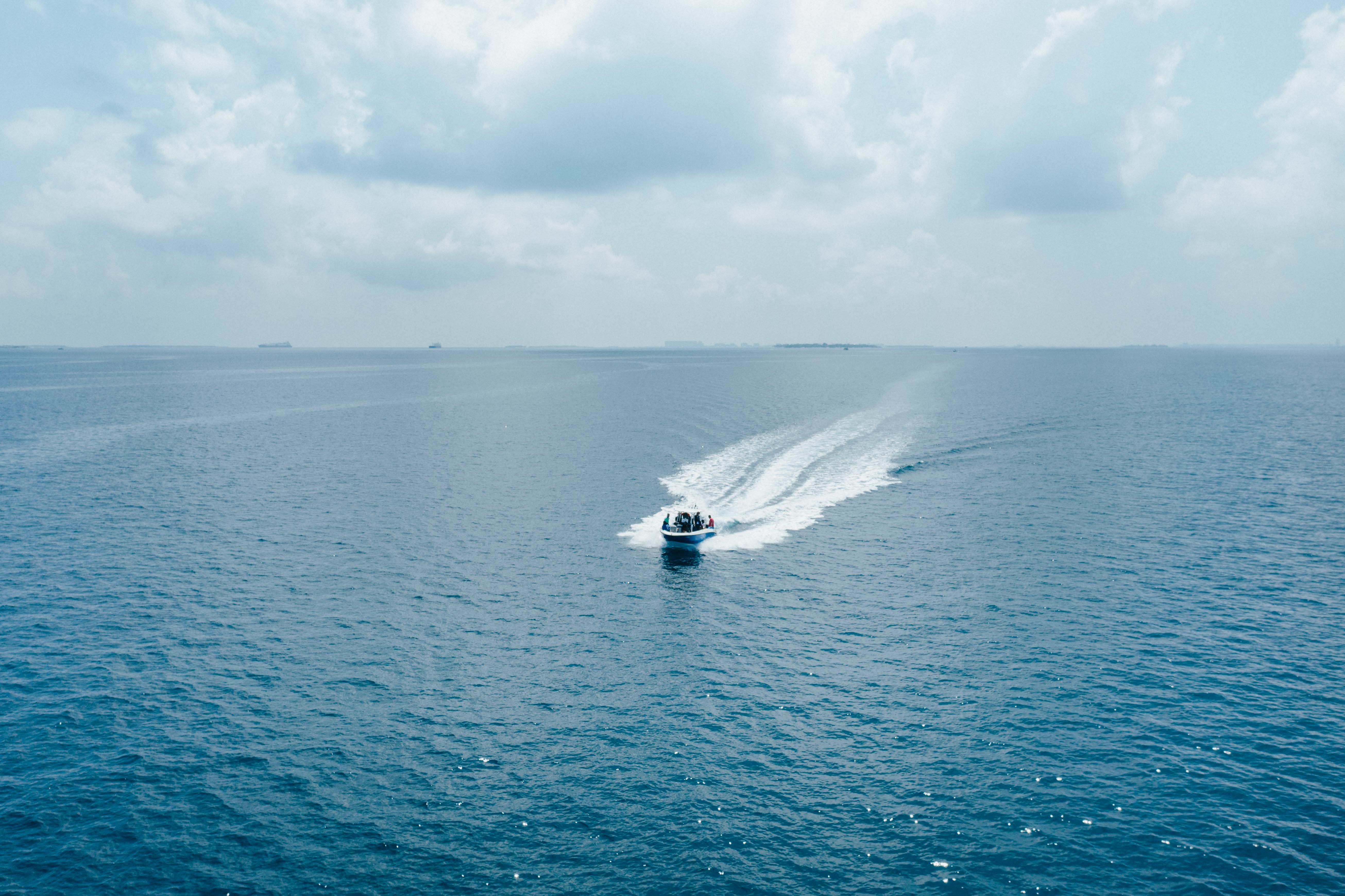 A speedboat speeding across clear turquoise waters in the Maldives, transferring tourists between islands.