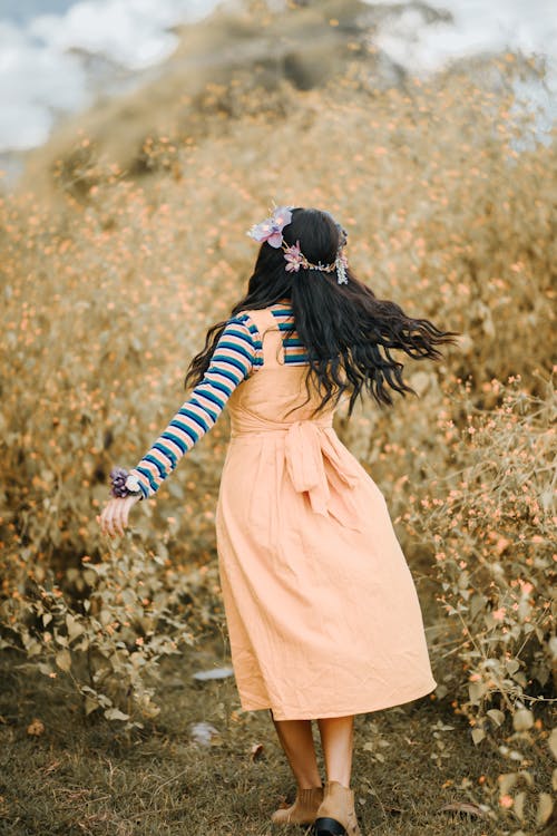 Free Unrecognizable woman in floral wreath near shrub on meadow Stock Photo