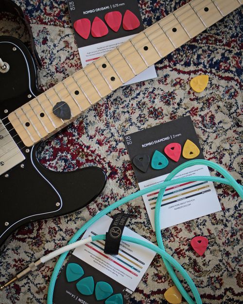 Free Electric guitar with various picks and cables on a colorful carpet. Stock Photo