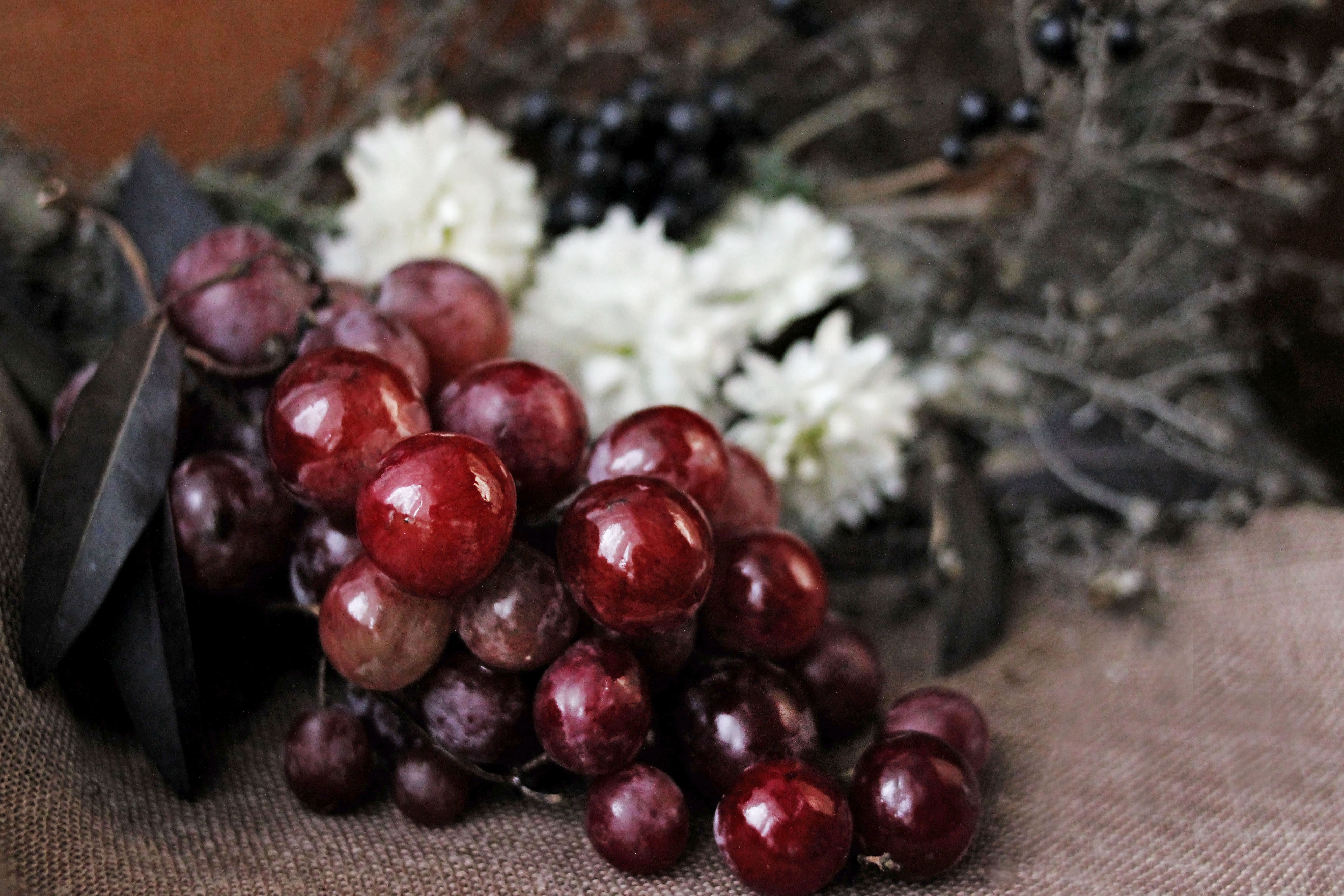 Close-up of fresh red grapes surrounded by flowers and foliage.