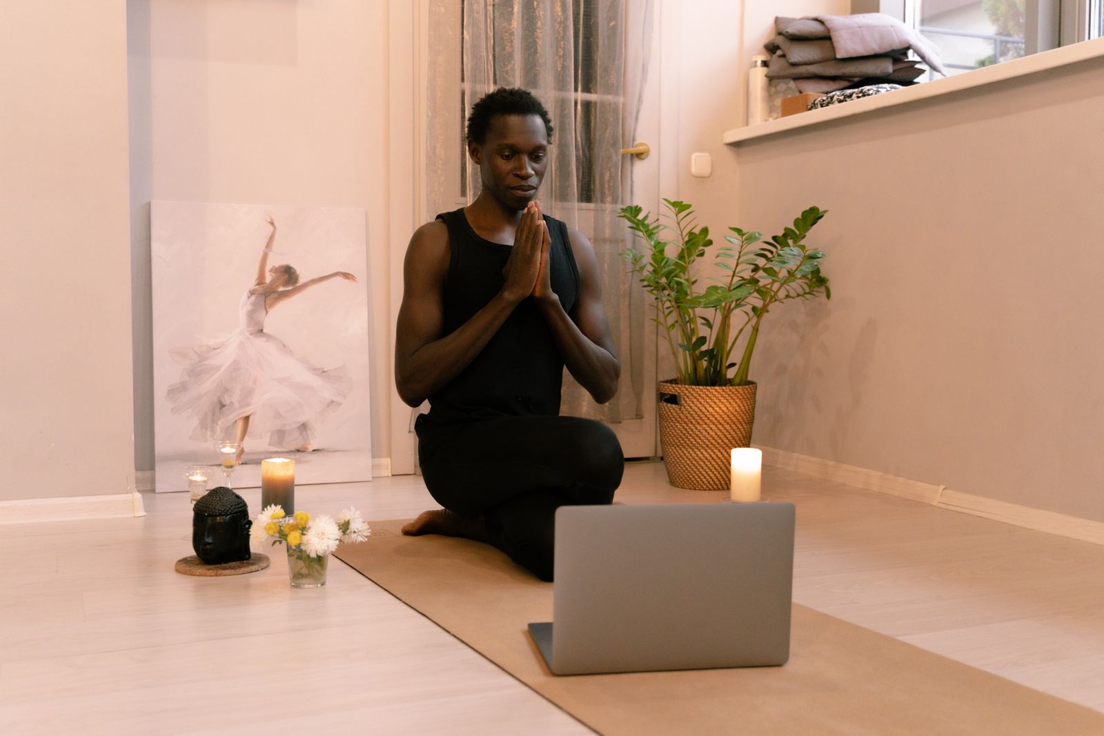 Woman completing online yoga teacher training at home with a laptop and yoga mat