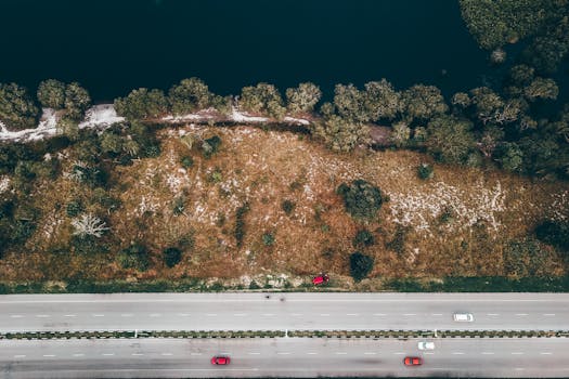 Drone view of asphalt roadways with driving vehicles near ocean beach with growing trees
