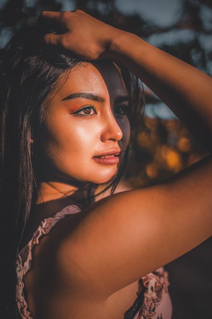 Portrait of focused young female in casual outfit with long hair touching head and looking away