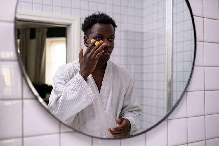 Man In Bathrobe Applying Under Eye Patch