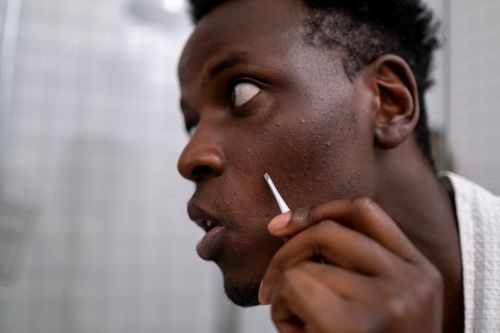 Free Side profile of a man using tweezers for skincare in a bathroom setting. Stock Photo