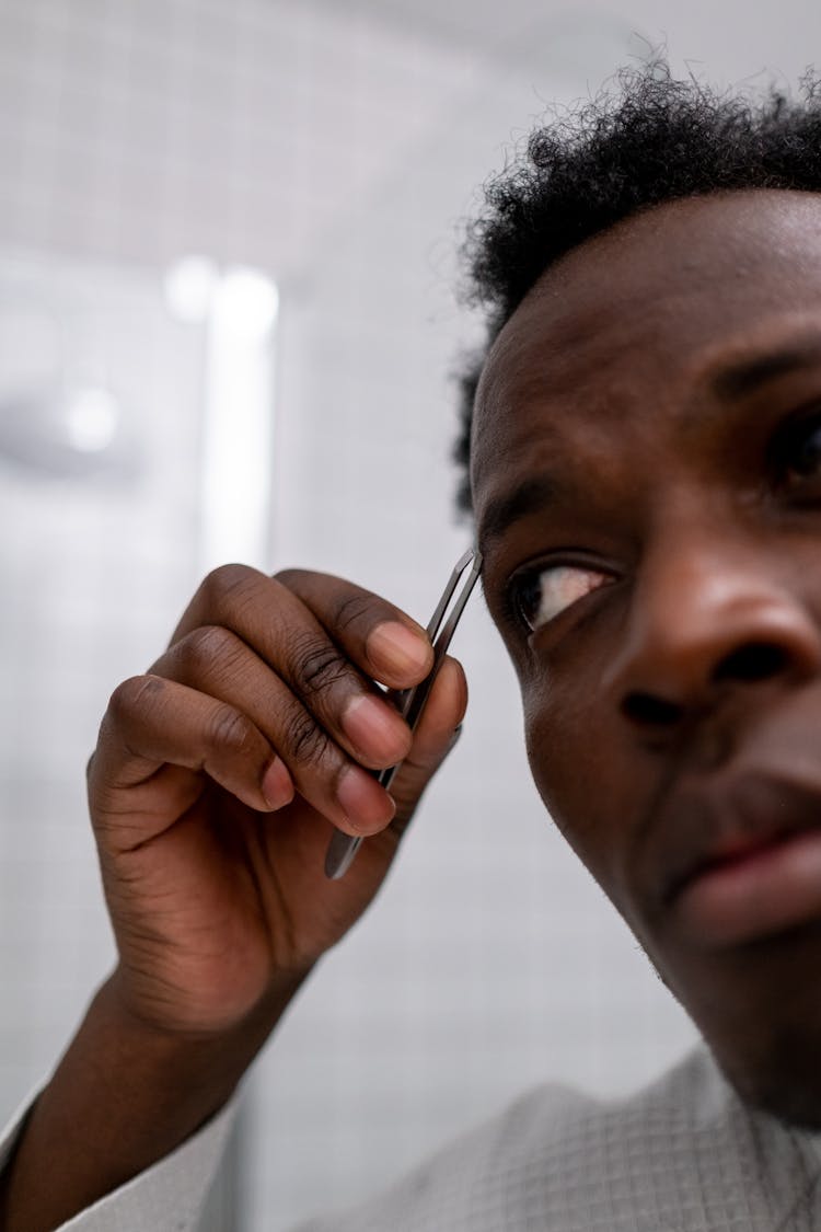 Man Plucking Eyebrows With Tweezers