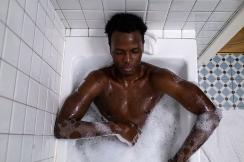 Free A man relaxing in a bathtub filled with bubbles, enjoying a calming bath experience indoors. Stock Photo