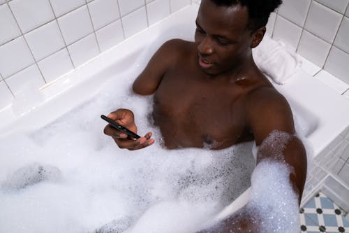 Free Man Using Cellphone While in the Bathtub Stock Photo