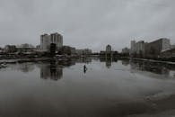 Calm pond surrounded by multistory buildings on cloudy day