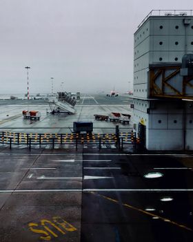 Foggy view of an airport runway and terminal in Lombardia, Italy with a grounded airplane.