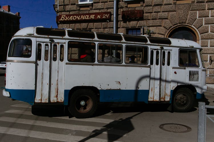 Old Bus With Passengers Driving On Road