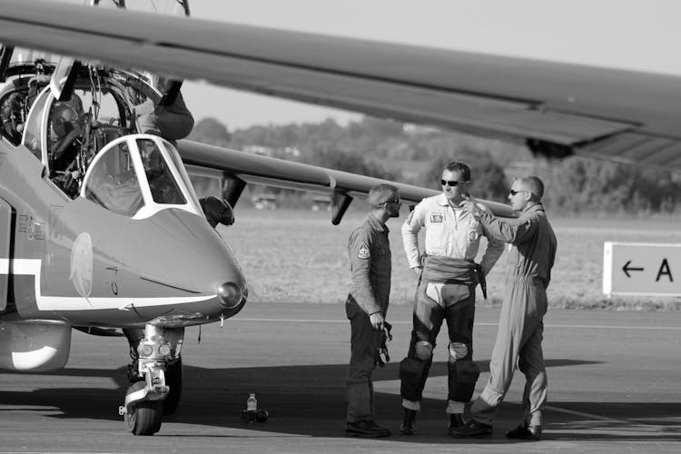 Black And White Photo Of Pilots Talking Next To Military Jet 