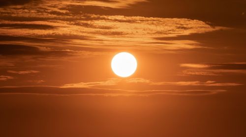 Free Captivating image of the sun setting over a vibrant golden sky filled with clouds, creating a dramatic scene. Stock Photo