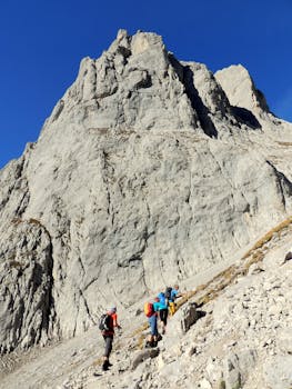 Group of hikers ascending a rugged mountain path under a clear blue sky in Tirol, Austria.