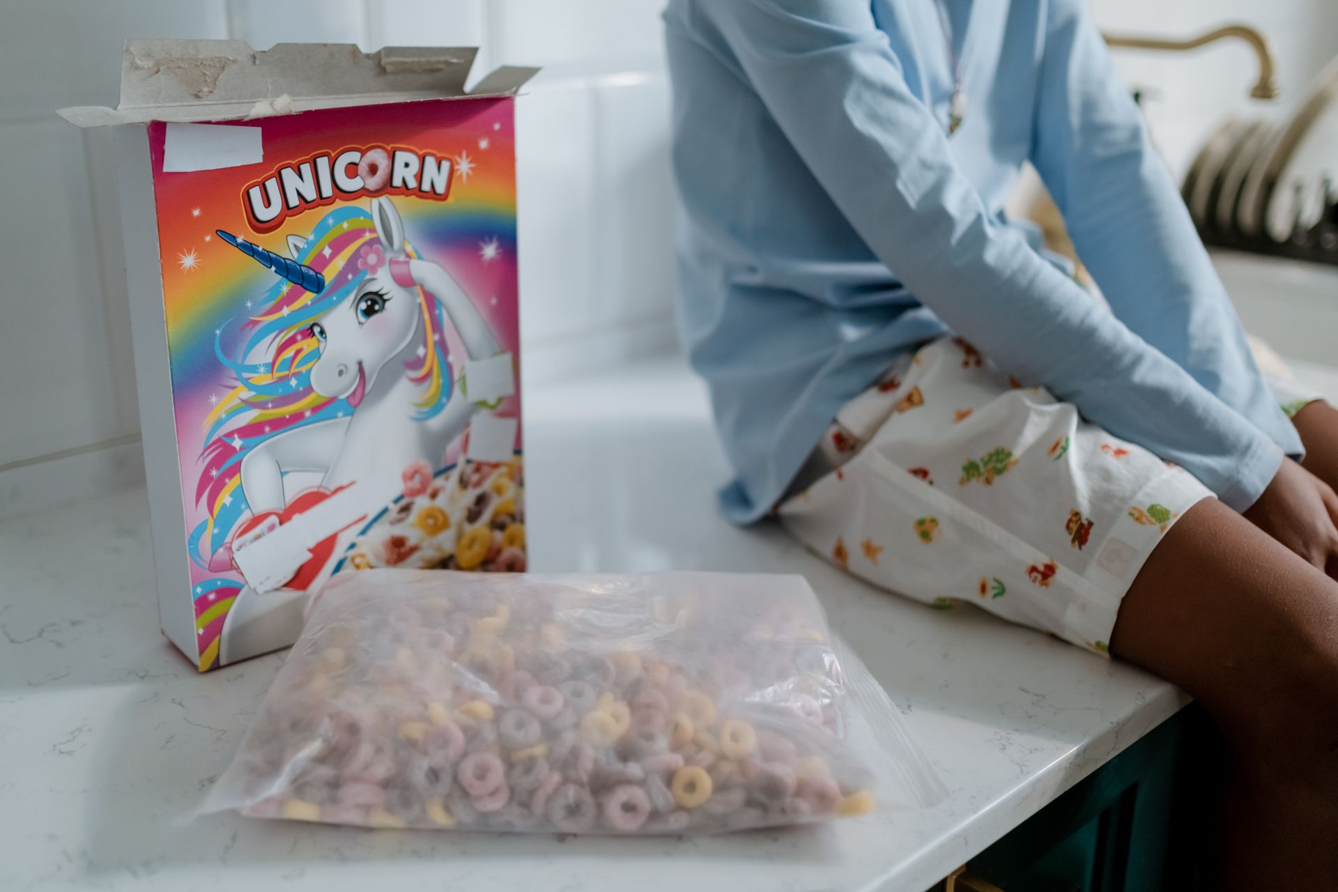 Person Sitting beside Cereal Box on White Counter Top