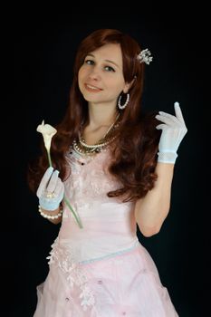 一位迷人的女子身着粉色礼服，佩戴着手套和珠宝，手里拿着一朵花