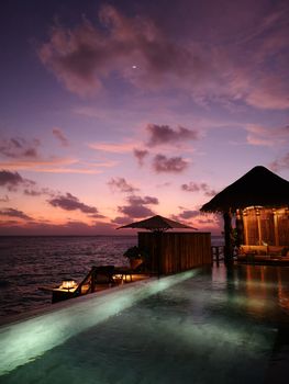Romantic sunset scene with a beach hut by the ocean, perfect for travel and relaxation.