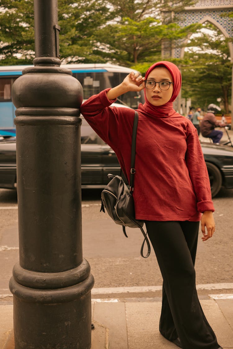 Woman In Red Long Sleeves Wearing Hijab Standing Beside Black Post