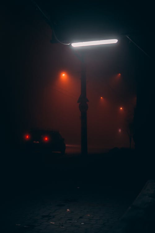 Silhouette of taillights of car and flashlights of city in haze at night