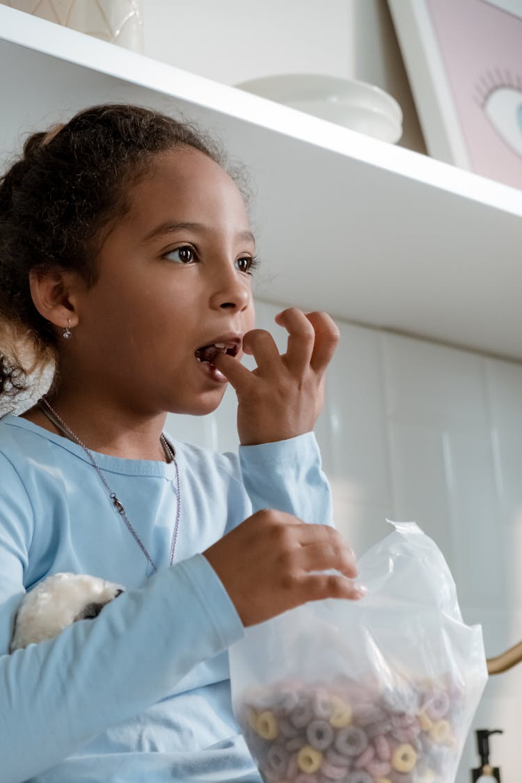 Girl In Blue Long Sleeve Shirt Eating Cereal