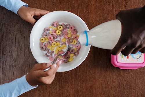 Free A Person Pouring Milk on Bowl of Cereals Stock Photo