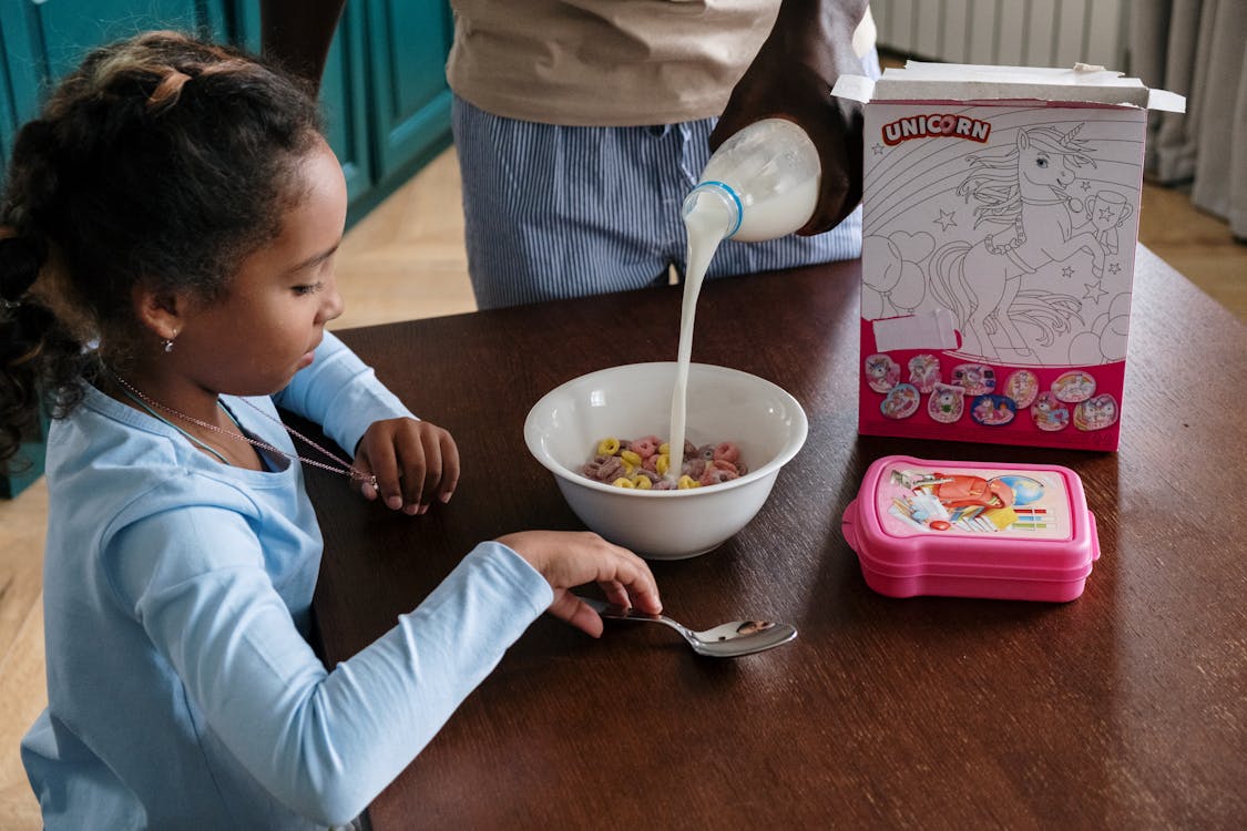 Person Pouring Milk on Cereals 