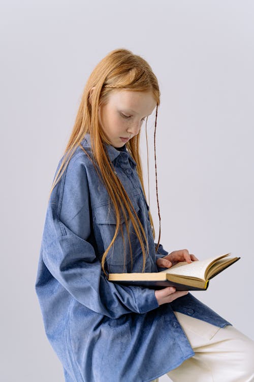 Free Girl in Blue Long Sleeves Reading a Book  Stock Photo