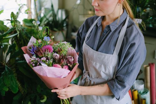 Free A woman florist holding a vibrant rustic bouquet in an indoor plant shop. Stock Photo
