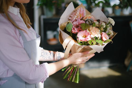 Woman in Pink Long Sleeve Shirt Holding Bouquet of Flowers
