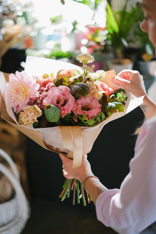 Free A woman gently holds a vibrant bouquet of mixed flowers indoors, creating a warm and intimate atmosphere. Stock Photo