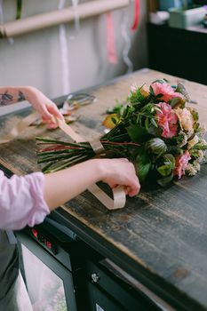 花艺师在室内的木桌上摆放了色彩缤纷的花束，展现了创造力