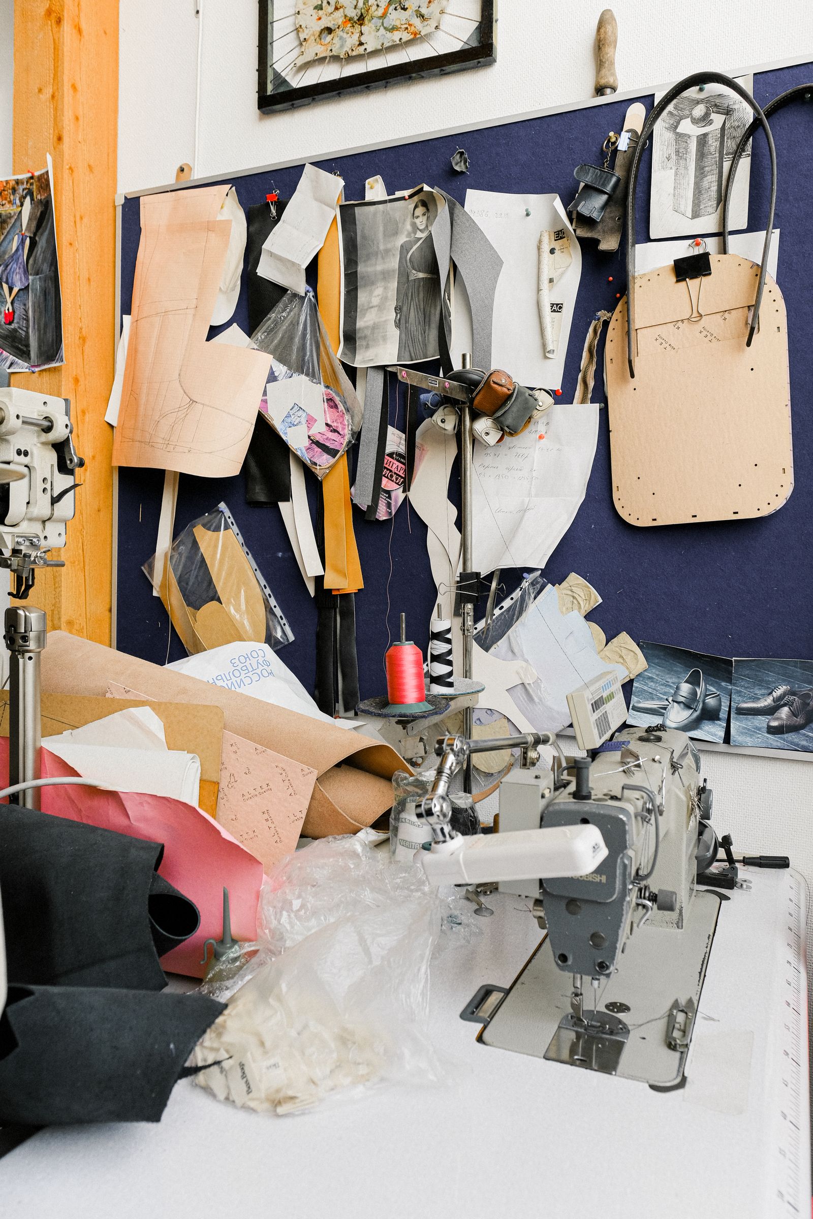 A shared studio floor with patterns pinned up and thread on every surface