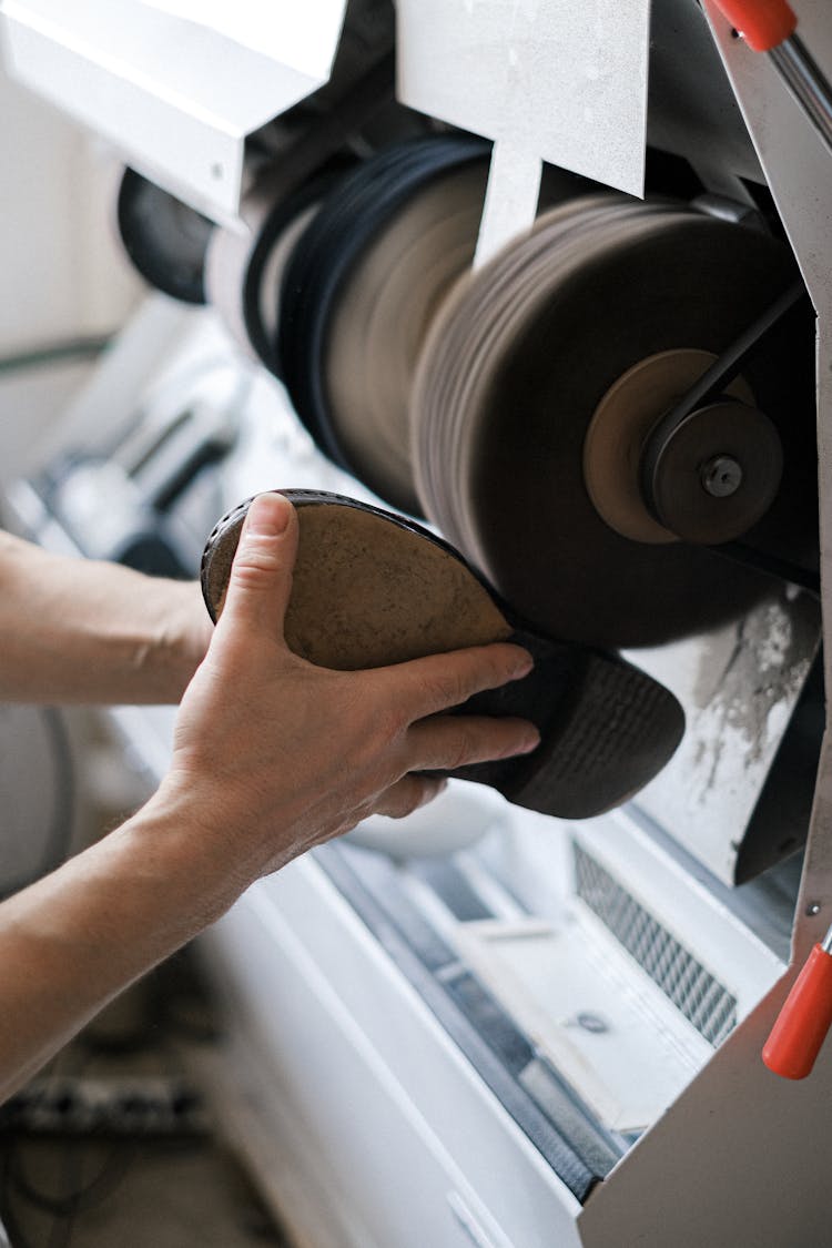 A Person Sanding A Leather Shoe