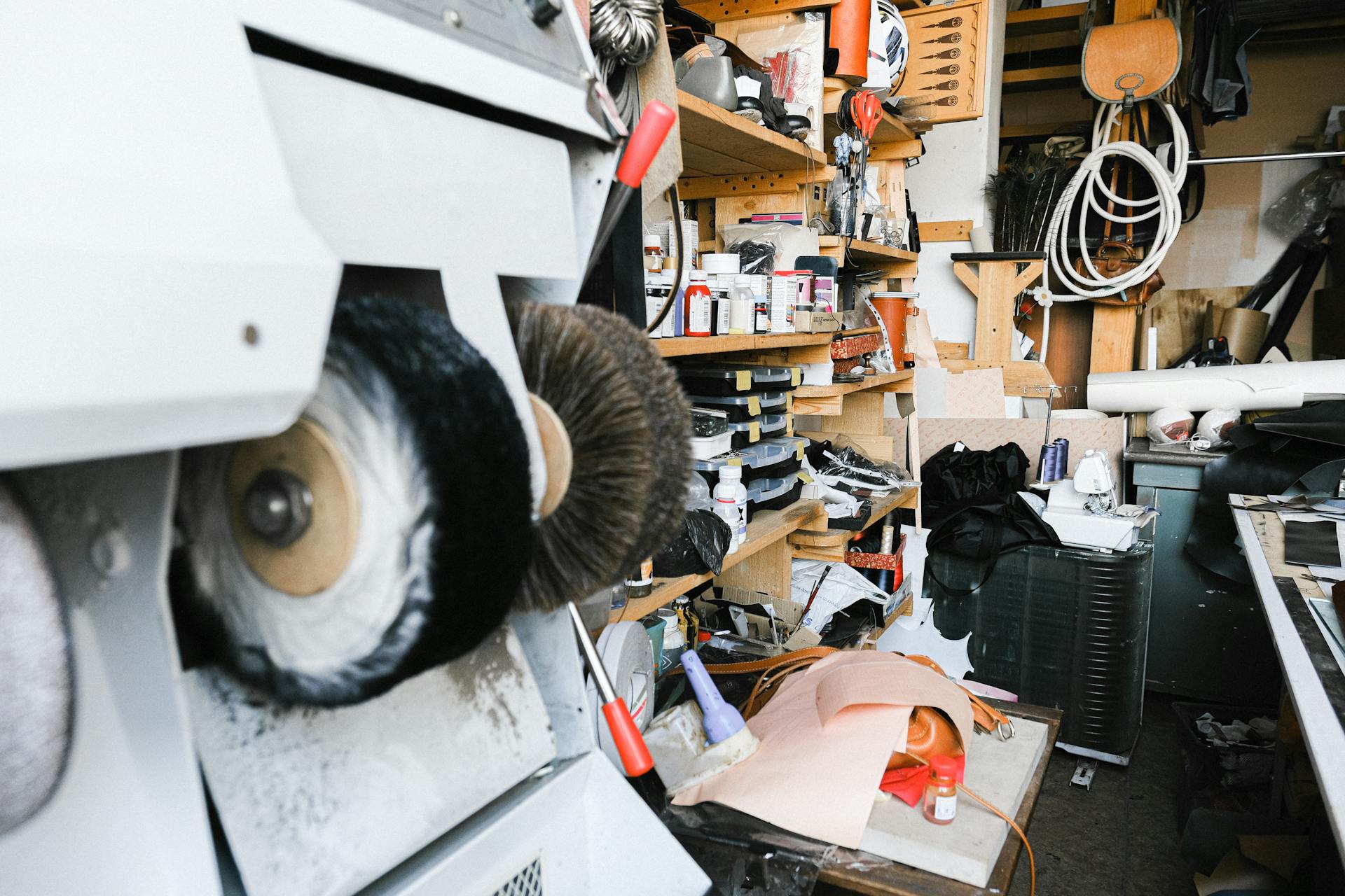 Busy workshop interior featuring a shoe polishing machine and various tools and supplies.