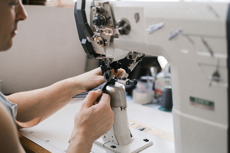Close-up of a leather artisan at work using an industrial sewing machine.