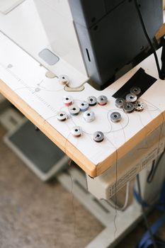 A detailed view of sewing machine bobbins and threads on a work surface in a crafting area.