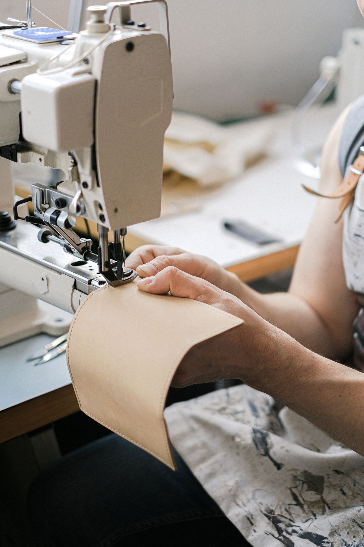 Leather artisan guiding a hide through an industrial sewing machine