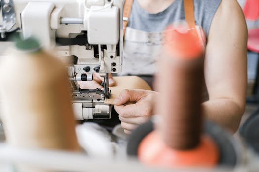 Close-up of a leather artisan sewing with an industrial machine in a workshop.