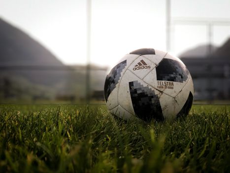 Close-up of an Adidas Telstar soccer ball on a grassy field at dusk in Switzerland.