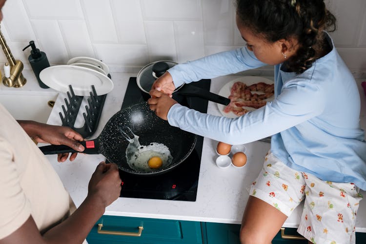 A Girl Cooking Eggs In The Kitchen