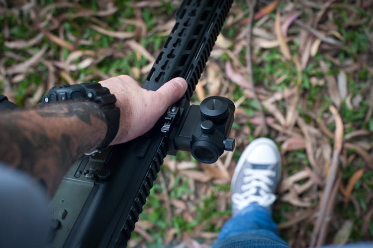 Person Holding Black Rifle Gun With Scope